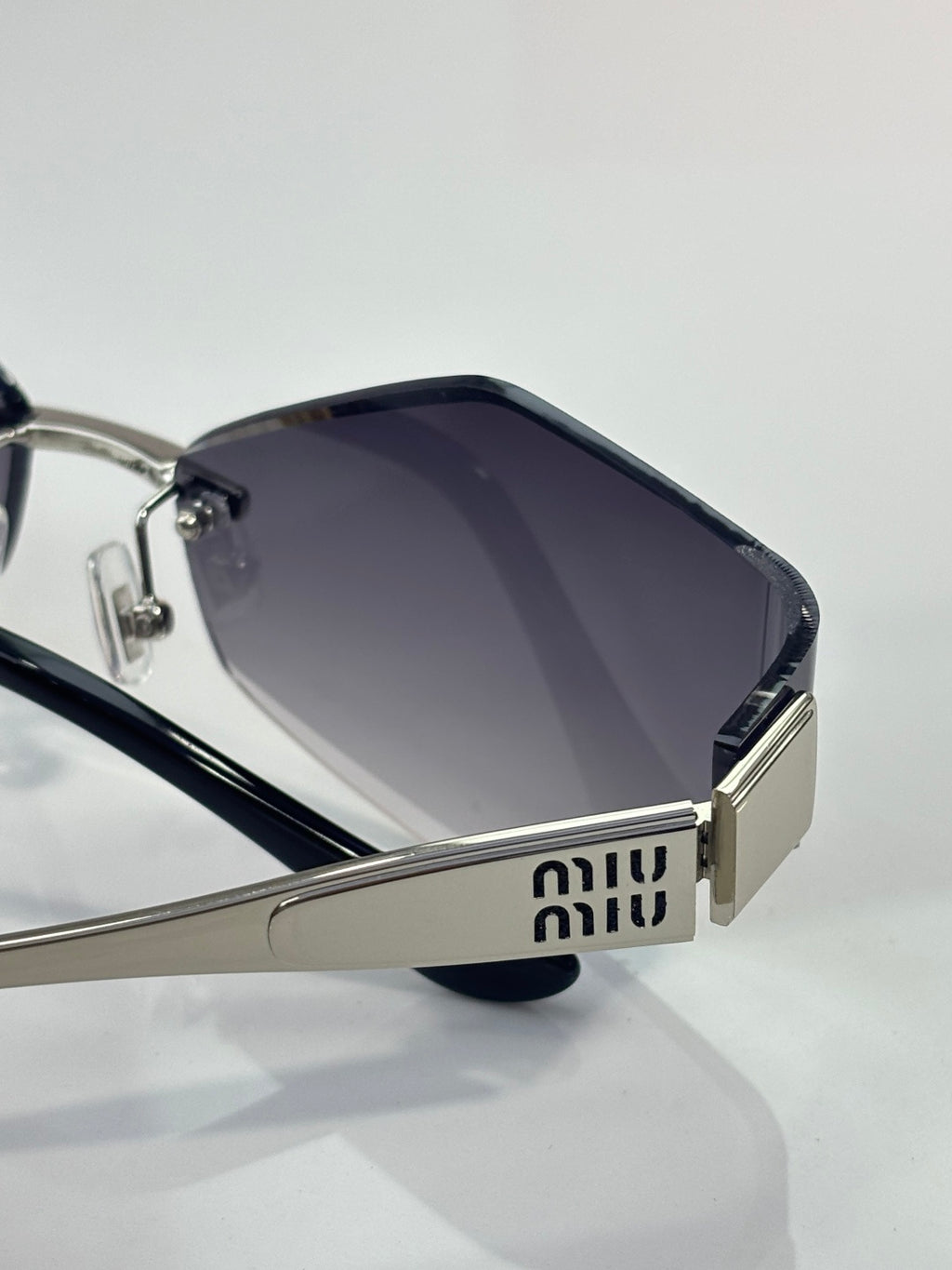 Sunglasses close-up: dark lenses with silver frame and Miu Miu logo plaque