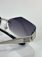Sunglasses close-up: dark lenses with silver frame and Miu Miu logo plaque