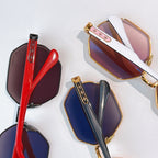 Octagonal sunglasses with gold frames and tinted lenses, shown with red and blue pairs