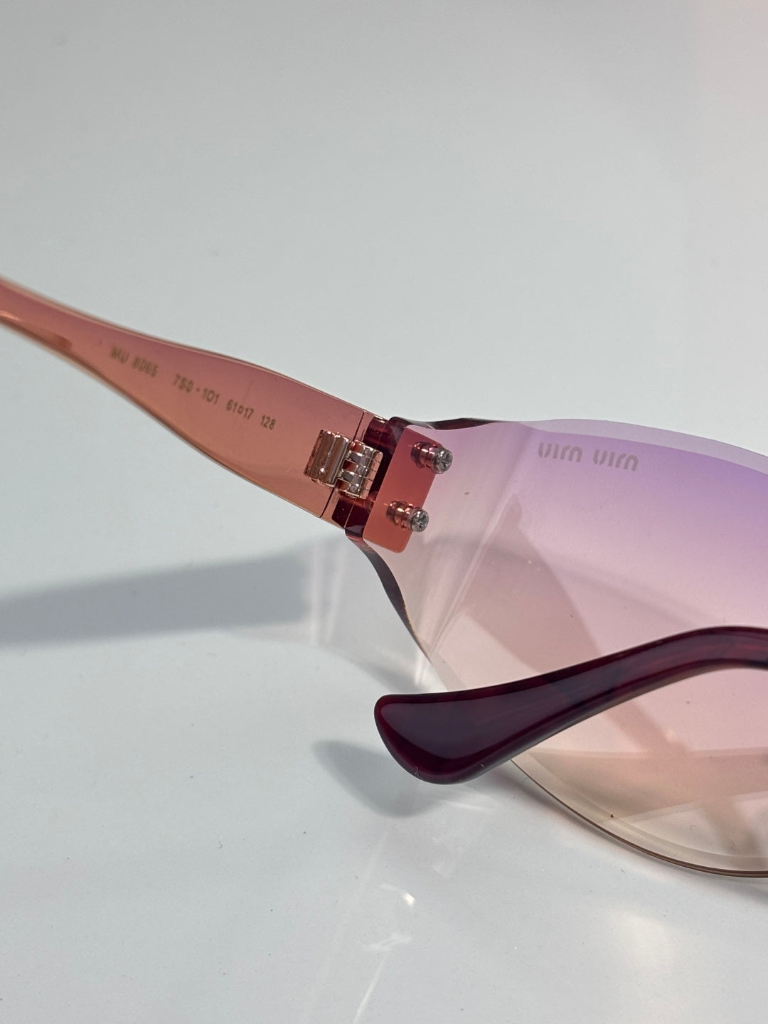 MiuMiu sunglasses close-up of side arm and lens with maroon frame, gold details