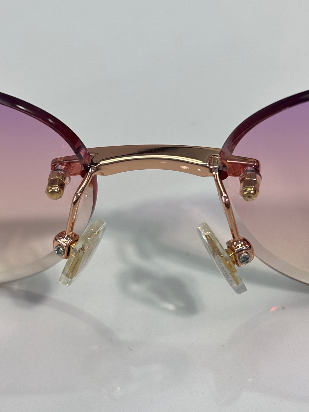 MiuMiu sunglasses close-up: maroon translucent frame, gold hinges, clear temples