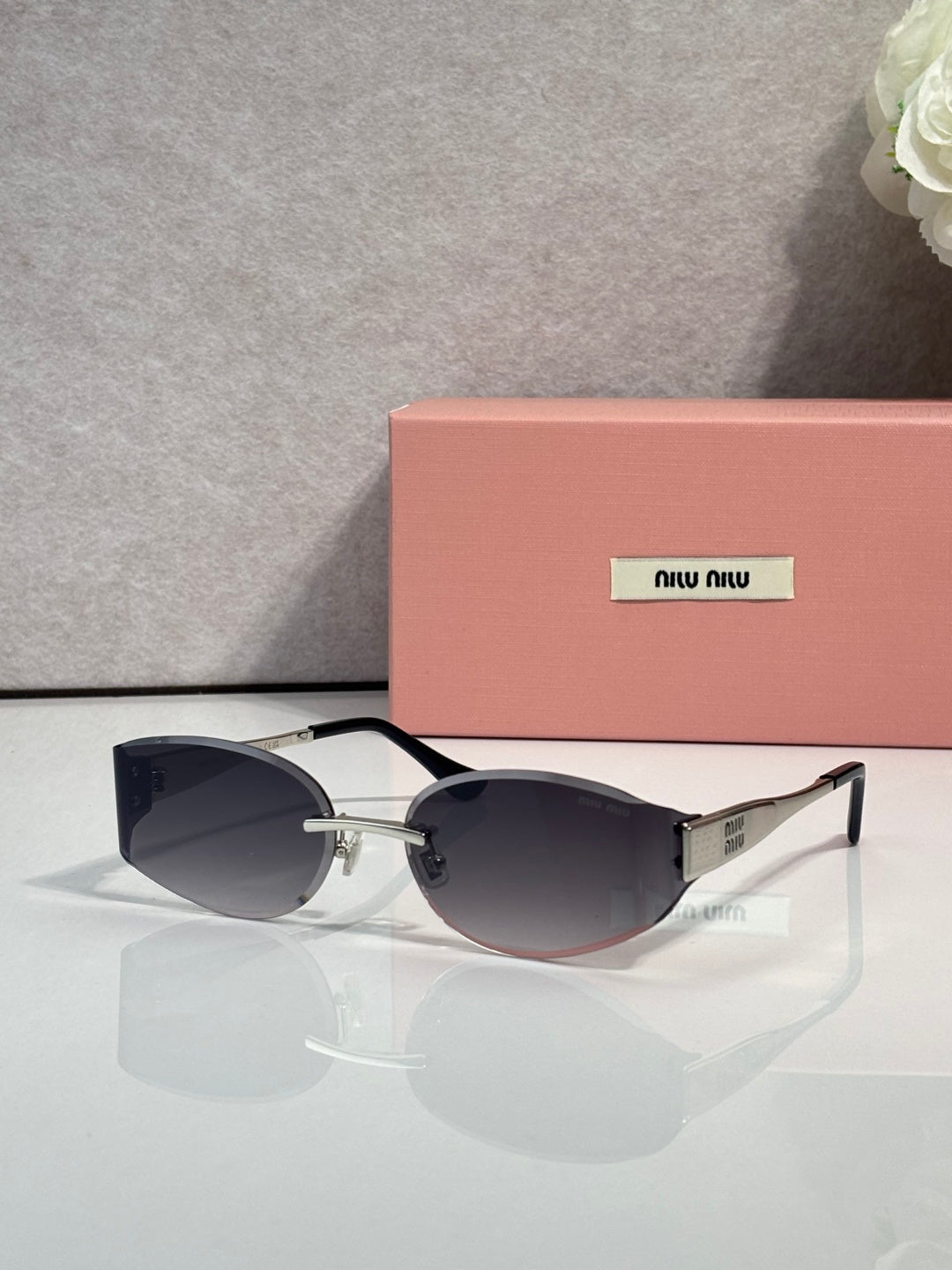 MiuMiu cat-eye sunglasses with dark navy lenses, maroon frame, gold accents
