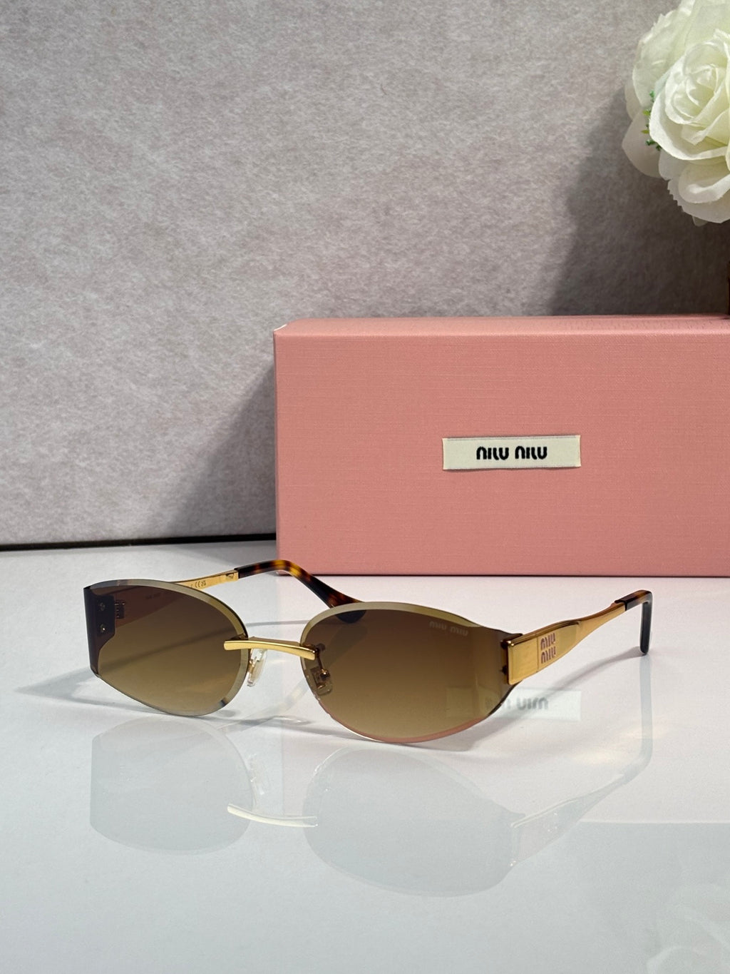MiuMiu cat-eye sunglasses with dark lenses, maroon acetate frame, gold accents