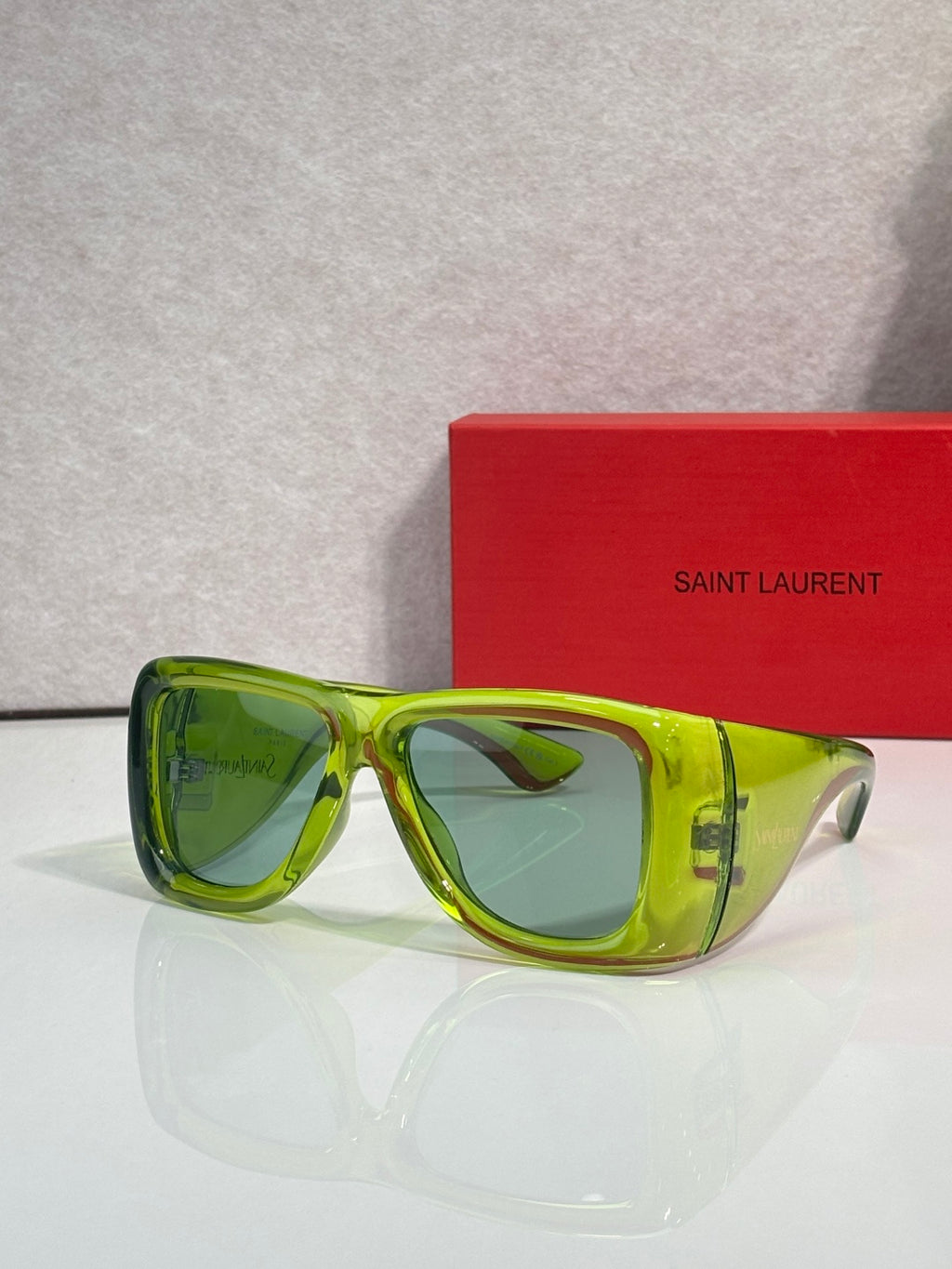 Green square sunglasses with tinted lenses and clear side arms, Saint Laurent