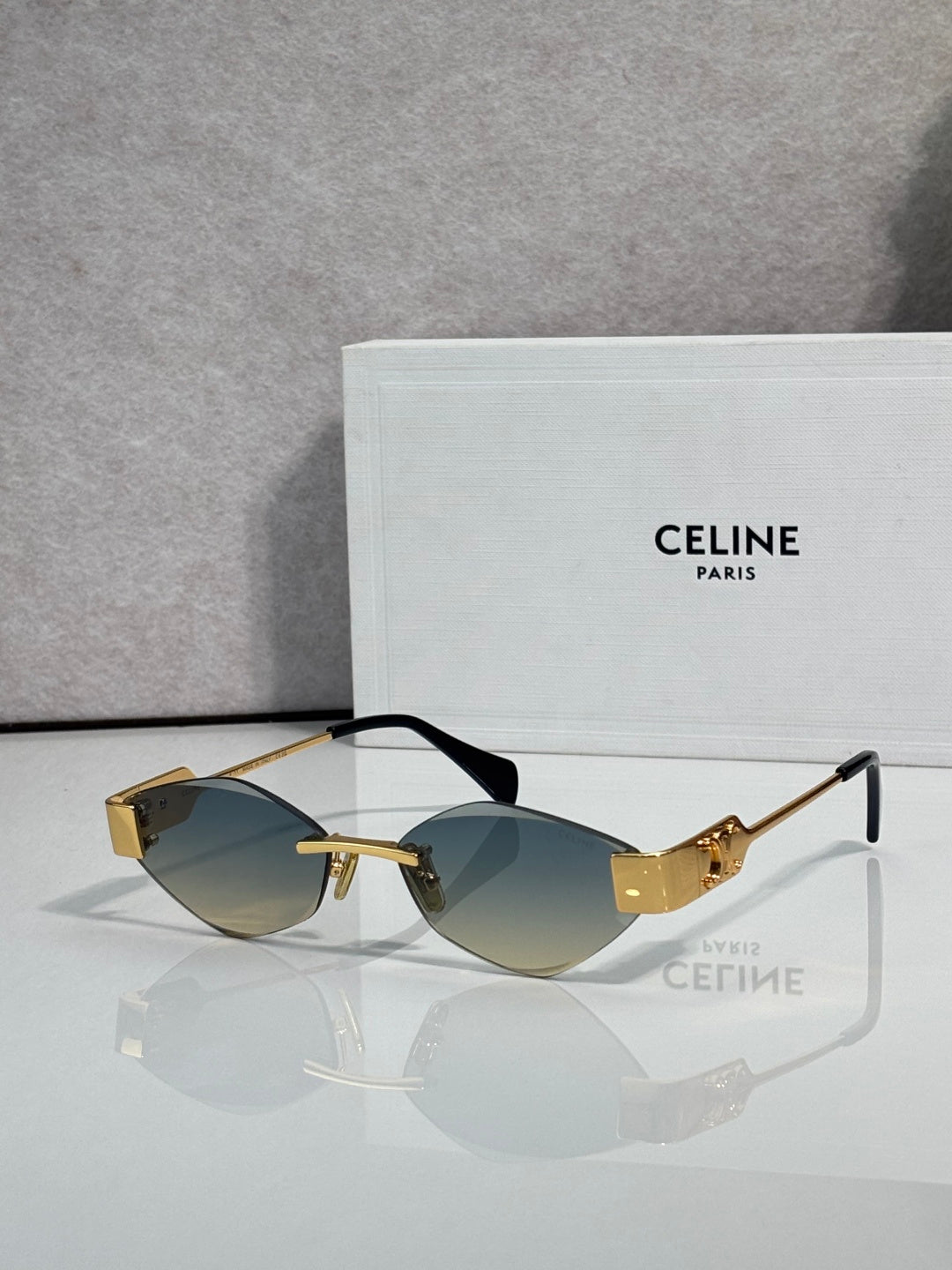 Celine sunglasses with green-tinted lenses, dark frame with gold-tone accents.