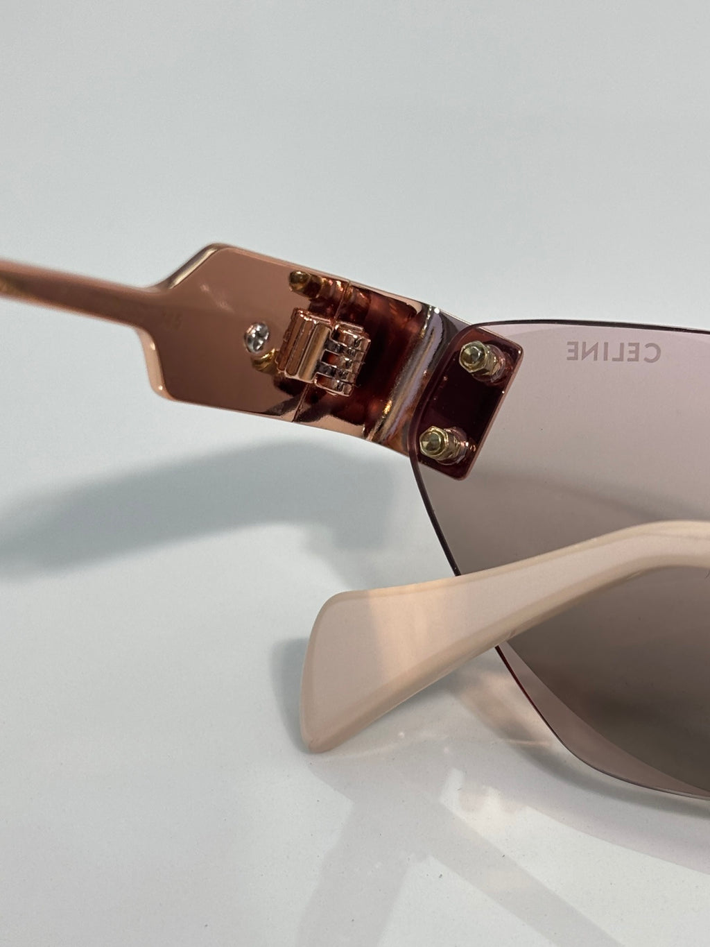 Celine sunglasses closeup: rose-gold frame hinge and transparent bridge bar.