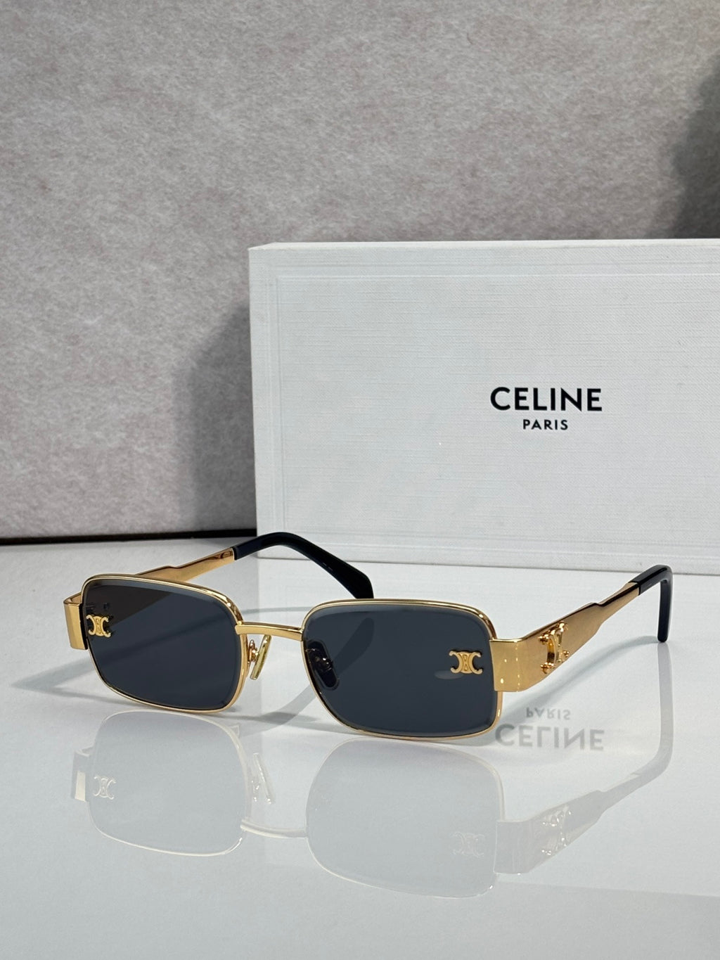 Gold-tone rectangular sunglasses, dark blue lenses, black temple accents