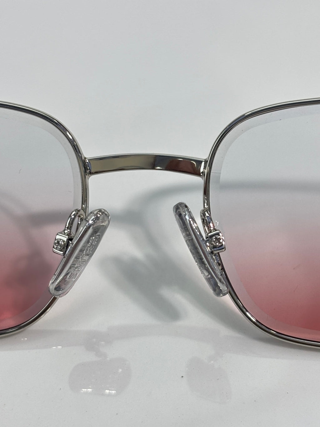 Silver-tone glasses with pink-tinted lenses and engraved hinge arms