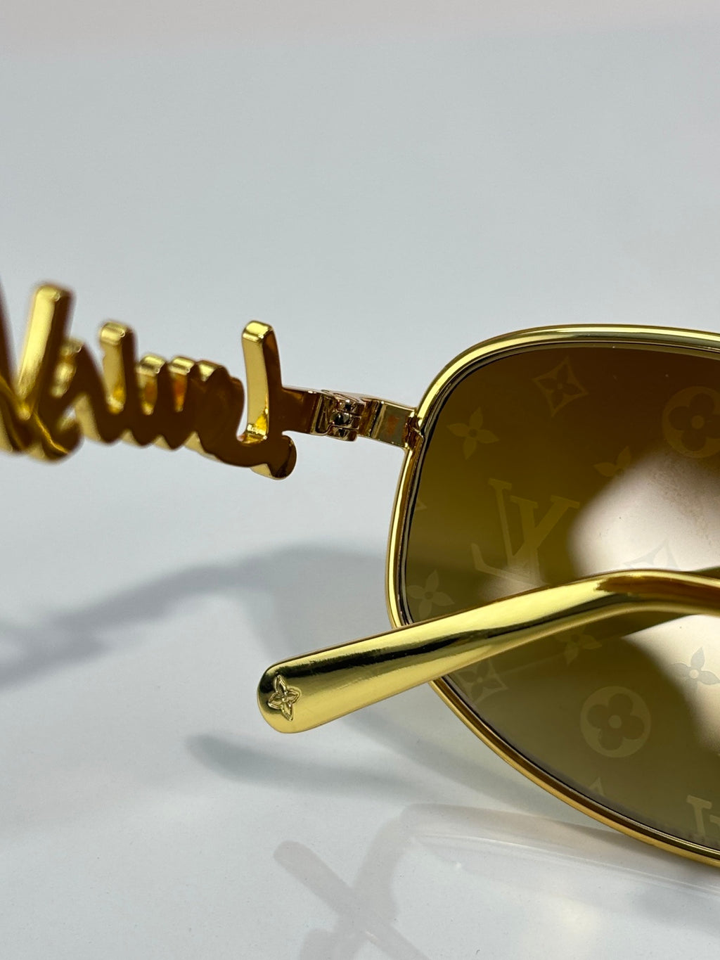 Louis Vuitton sunglasses close-up: gold arm with branding and gold frame detail