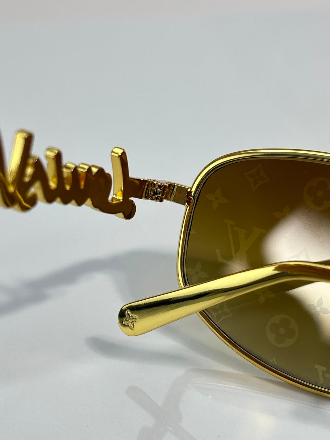 Louis Vuitton sunglasses close-up: gold arm with branding and gold frame detail
