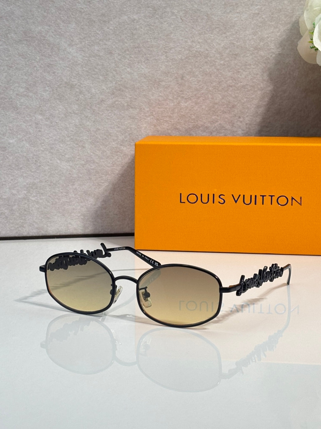 Louis Vuitton sunglasses with black frames and dark lenses, decorative side details