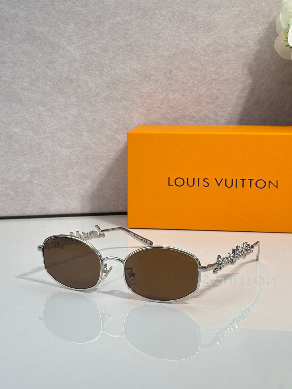 Louis Vuitton sunglasses with silver frames and brown lenses, decorative side detail