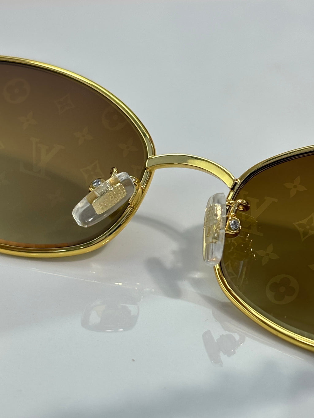 Louis Vuitton sunglasses close-up: gold round lenses with monogram and hinge detail