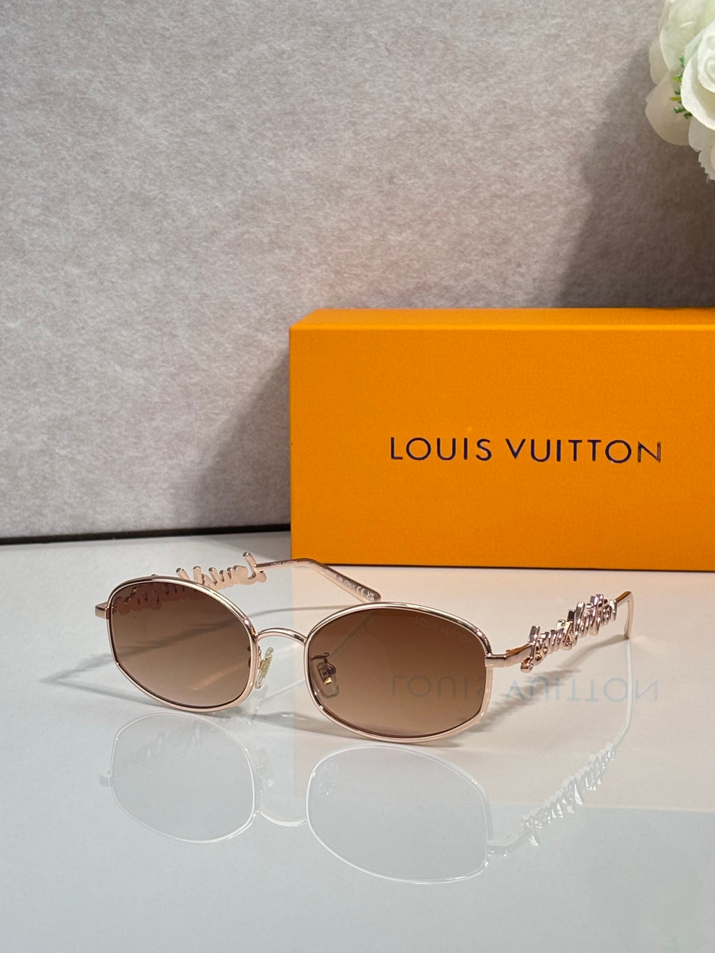 Louis Vuitton sunglasses with light rose-gold frames and brown lenses, ornate temple