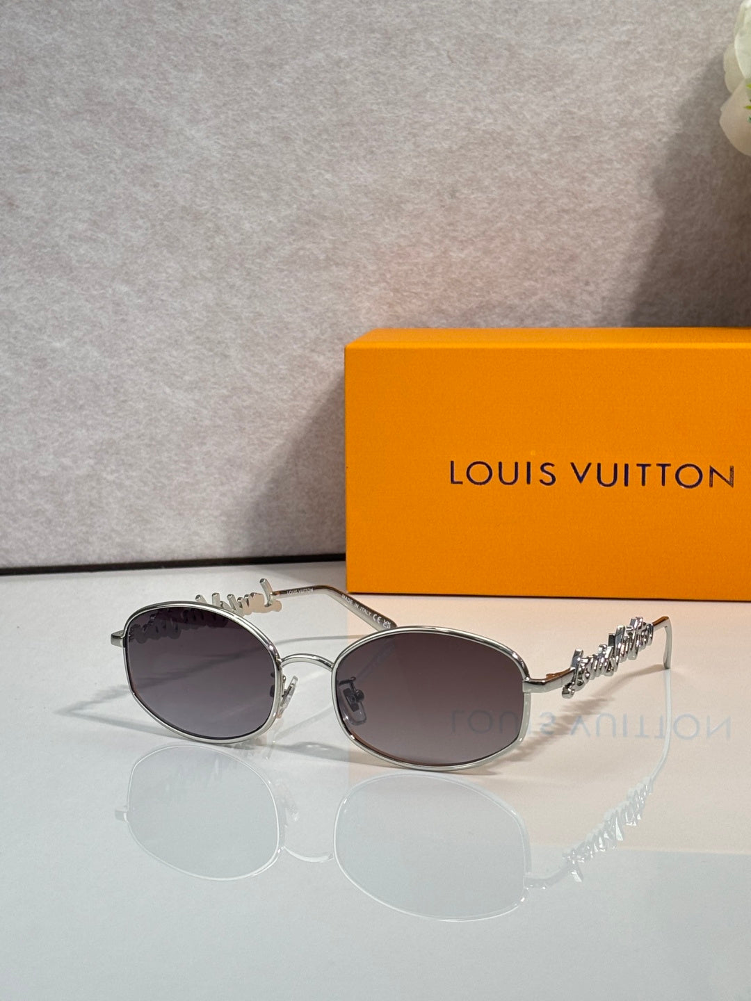Louis Vuitton sunglasses with silver frames and dark lenses, ornate temple detail