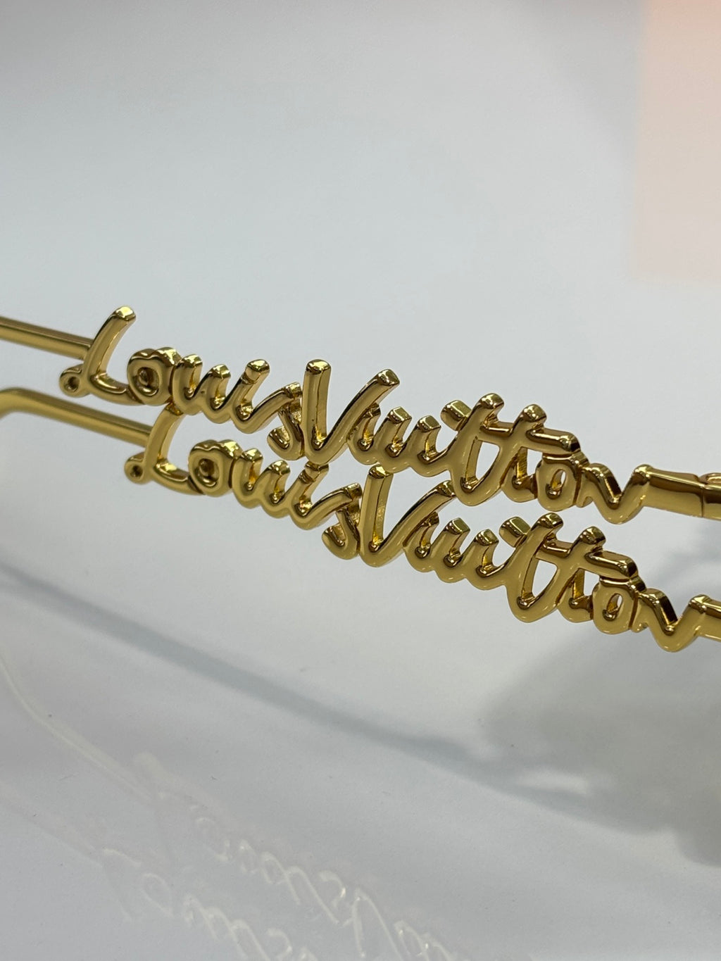 Close-up of Louis Vuitton glasses arm with gold cursive logo detailing