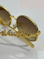 Close-up of Louis Vuitton round glasses with gold frame and amber tinted lenses