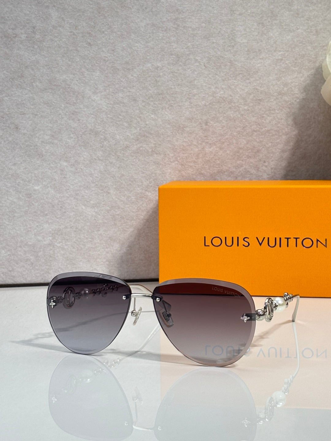 Louis Vuitton oval sunglasses with dark lenses and shiny metal frame