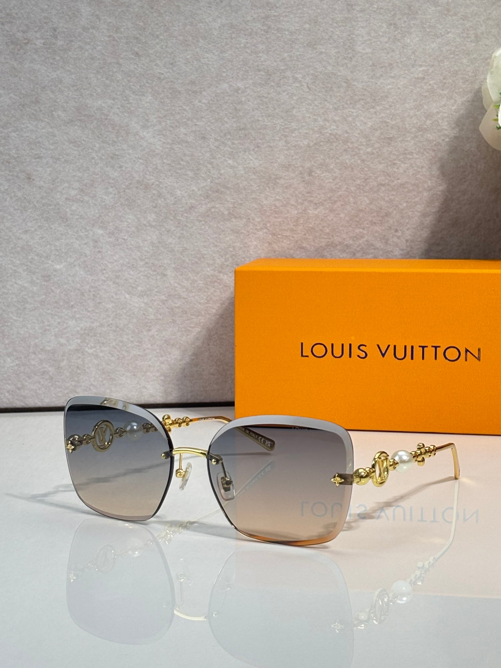 Sunglasses with light gray gradient lenses and gold-tone metal arms with charm detail
