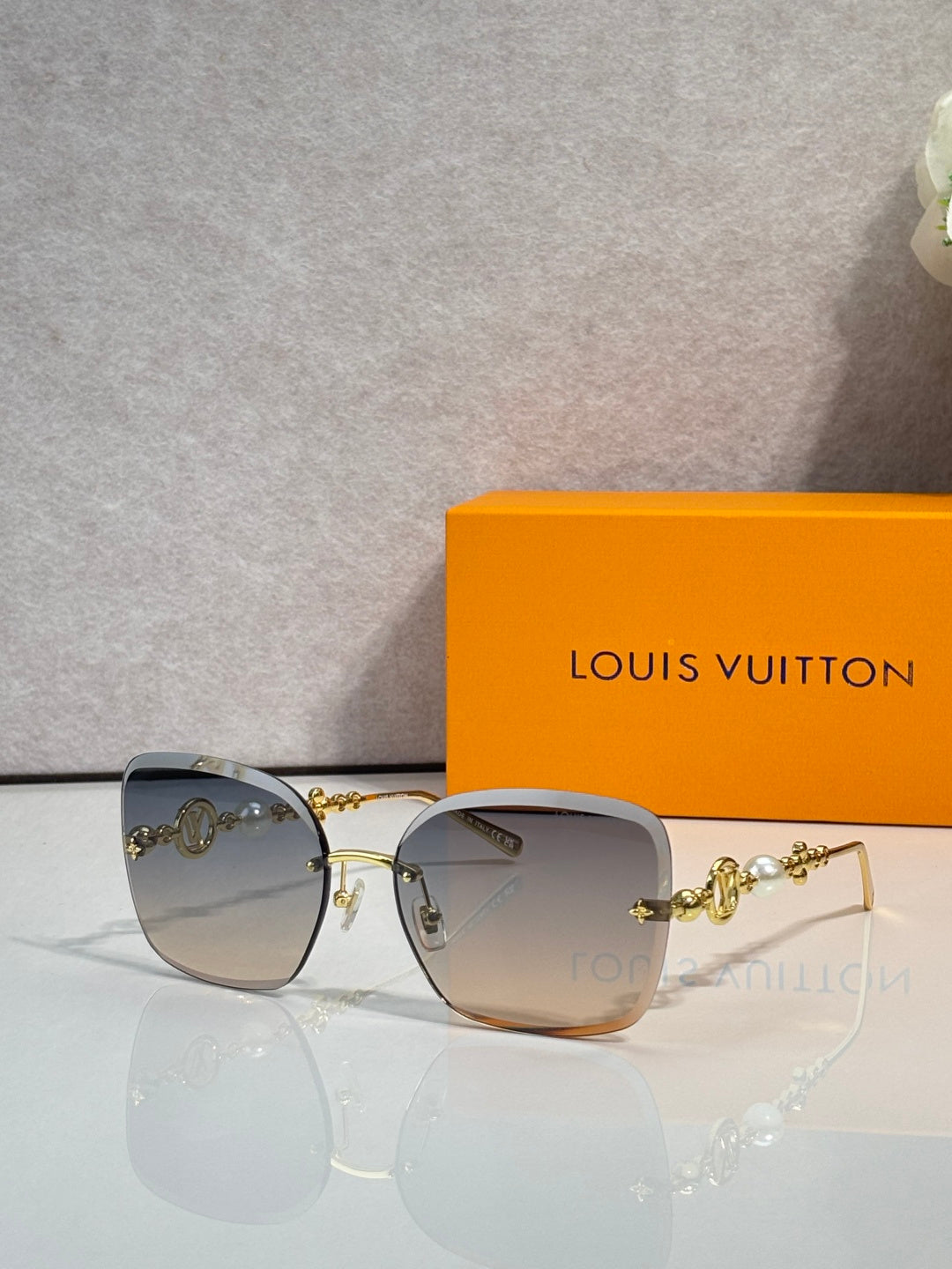 Sunglasses with light gray gradient lenses and gold-tone metal arms with charm detail
