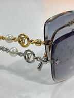 Sunglasses close-up: gold-tone temple chain with pearl beads and LV logo charms