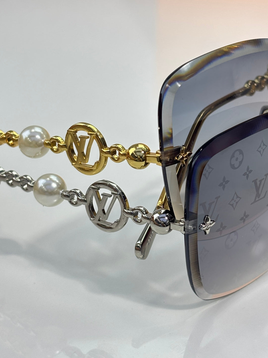 Sunglasses close-up: gold-tone temple chain with pearl beads and LV logo charms