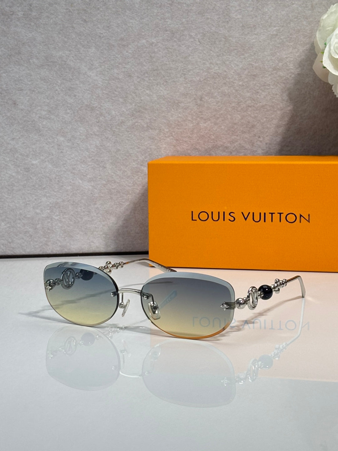 Louis Vuitton sunglasses with blue-tinted lenses and gold metal frame, beaded charm detail