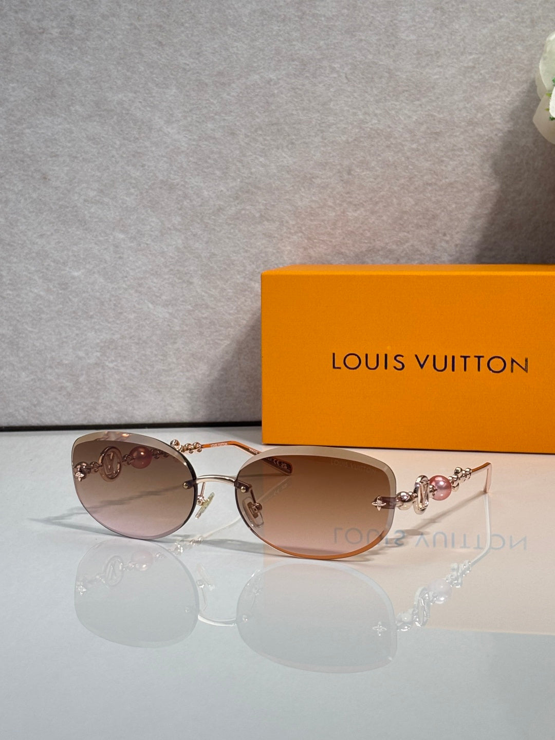 Louis Vuitton sunglasses with pink-tinted lenses and gold metal frame, pearl-bead accents