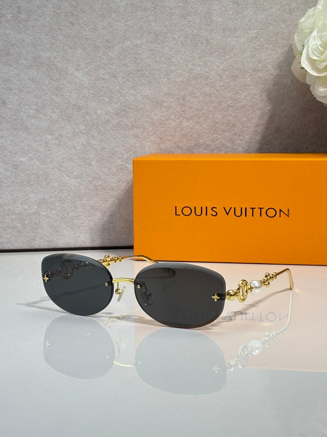 Louis Vuitton sunglasses with black lenses and gold metal frame, bead charm accents