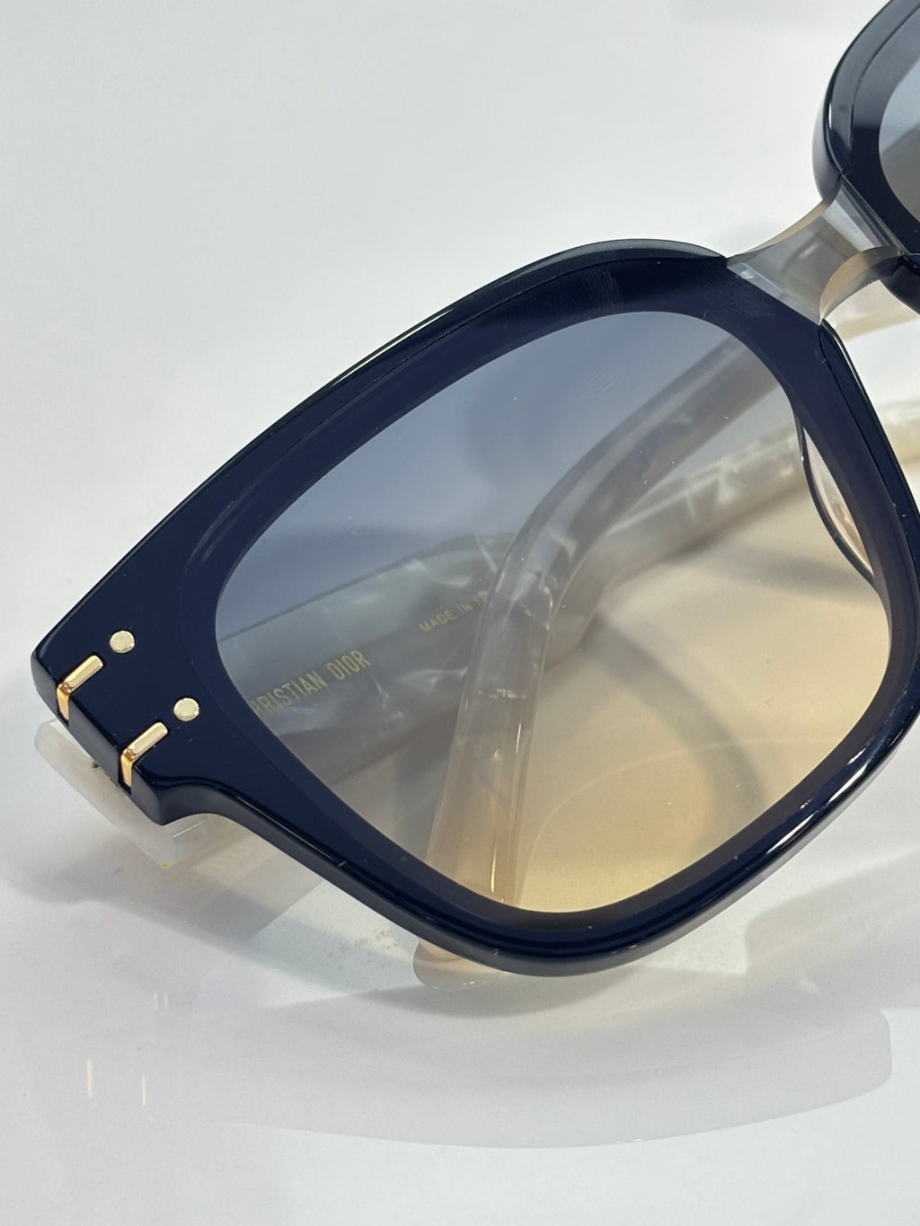 Sunglasses side frame with gold rivet details and amber gradient lens