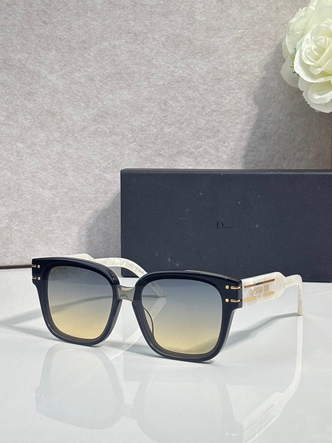 Sunglasses with black acetate frame and gradient lenses, gold logo detail at temple