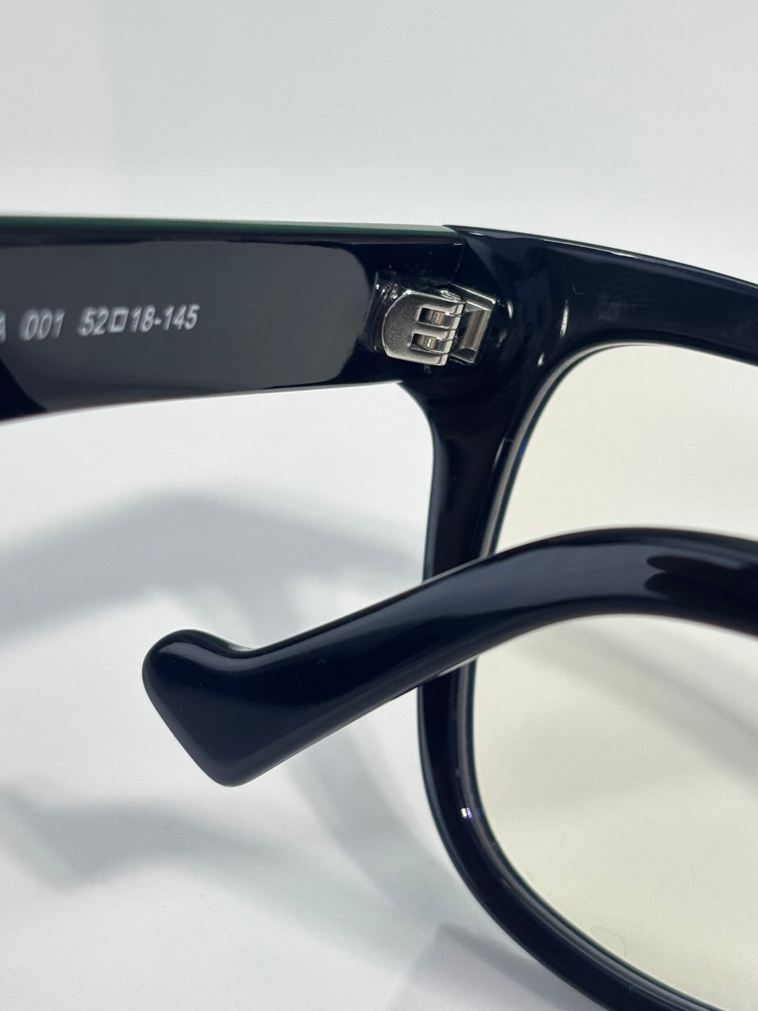 Glasses hinge with dark navy frame and gold detail, clear lens visible