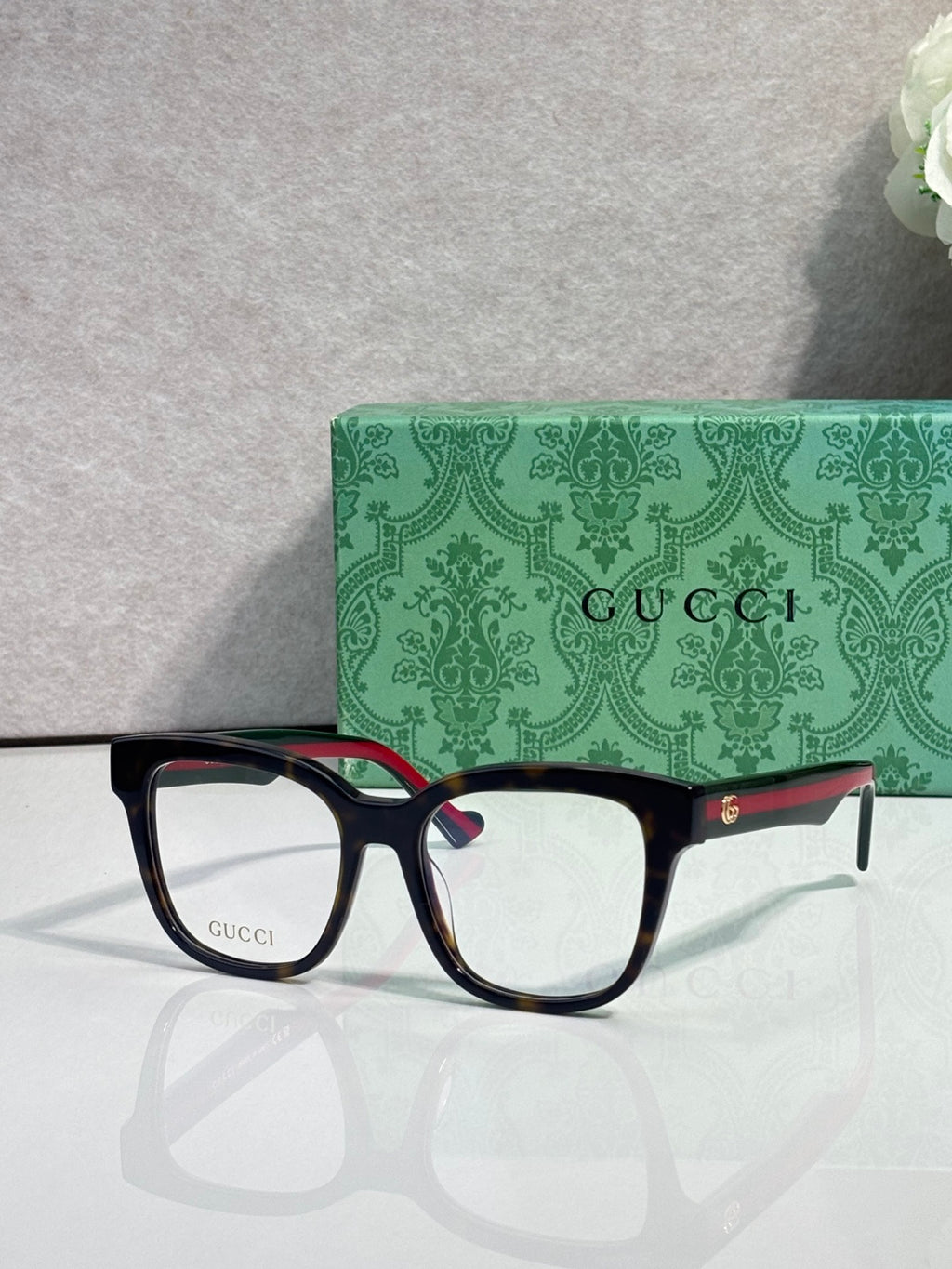 Rectangular eyeglasses with dark navy frame and gold logo details, clear lenses