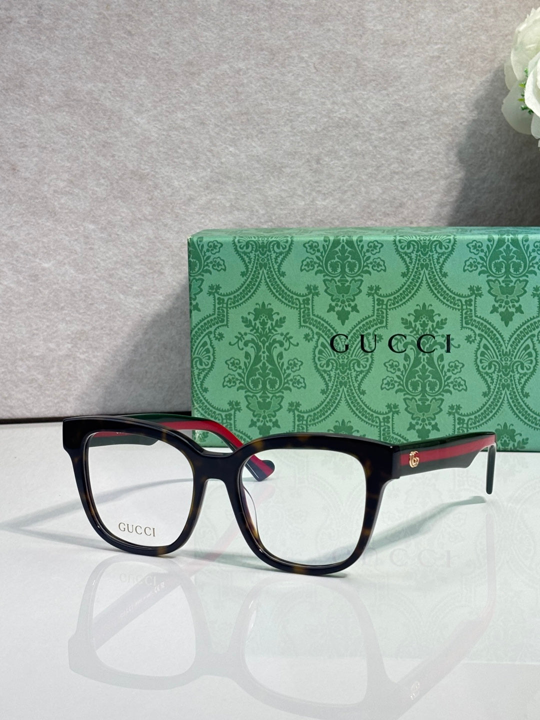 Rectangular eyeglasses with dark navy frame and gold logo details, clear lenses