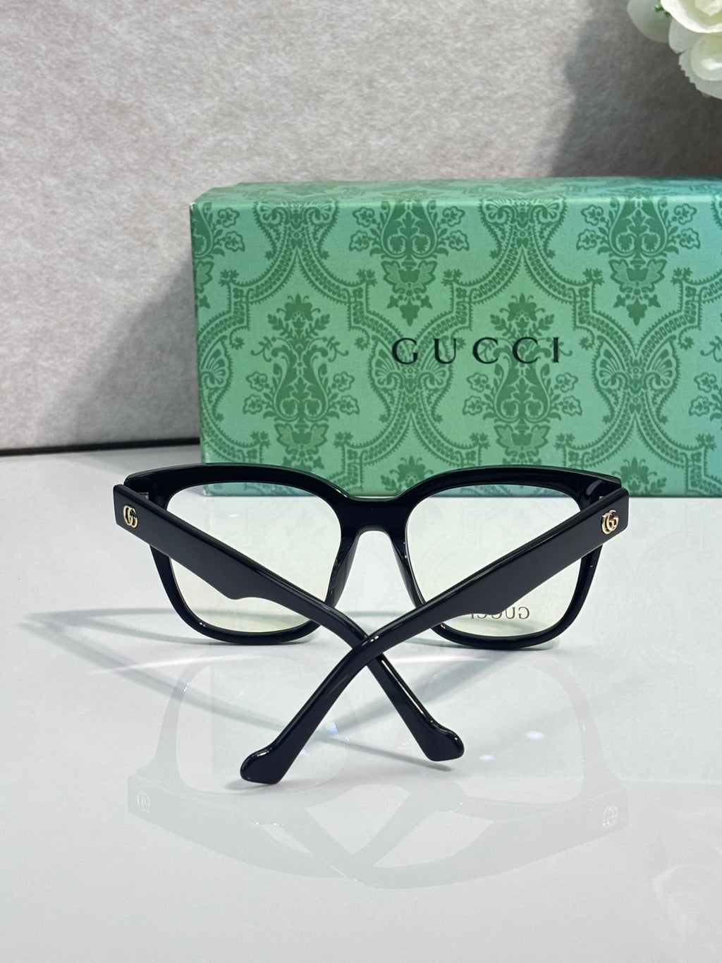 Rectangular eyeglasses with dark navy frame and gold double-G emblems, clear lenses