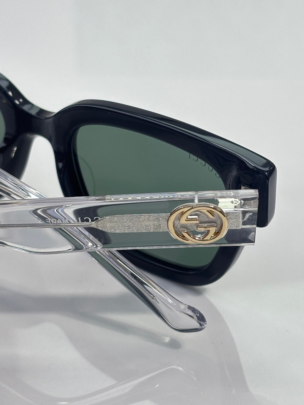 Gucci glasses detail, gold GG emblem on silver temple, dark lens
