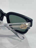 Gucci glasses detail, gold GG emblem on silver temple, dark lens