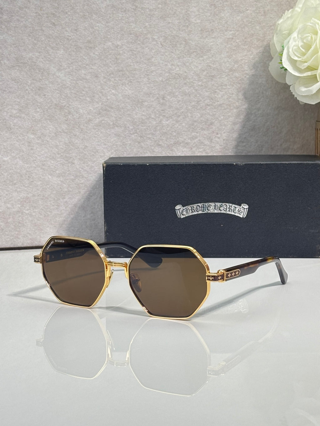 Chrome sunglasses with dark octagonal lenses and gold metal frame with white side arms
