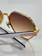 Chrome sunglasses close-up: gold frame, gradient lens, and side logo detail
