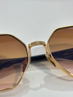 Chrome sunglasses close-up: gold frame with warm gradient lens and side arm text
