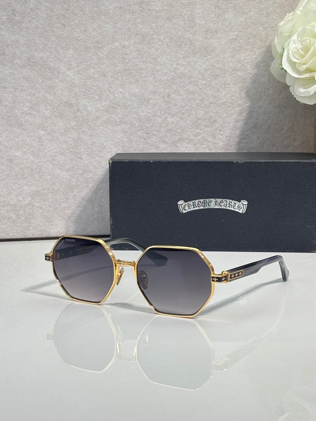 Chrome sunglasses with dark octagonal lenses and gold metal frame with white side arms