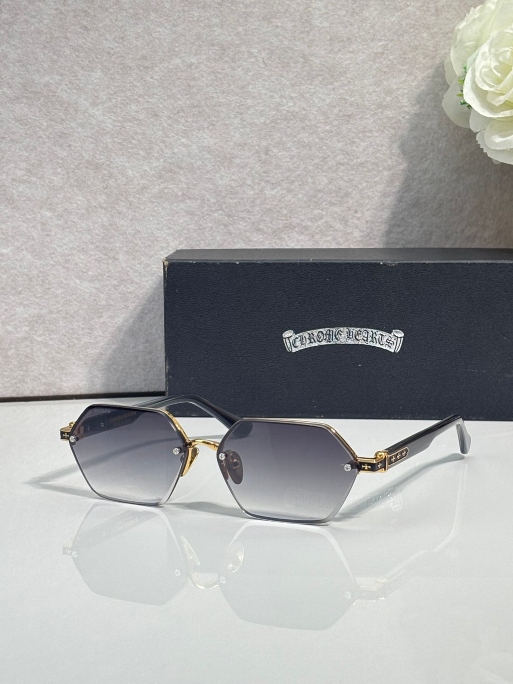 Hexagon sunglasses with blue-gray lenses and gold metal frame, black top bar