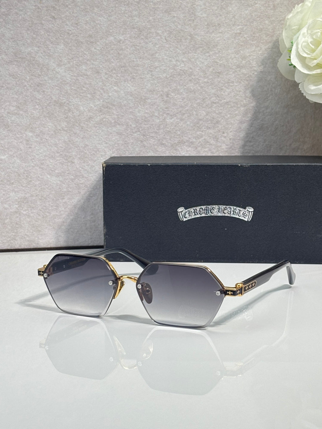 Hexagon sunglasses with blue-gray lenses and gold metal frame, black top bar