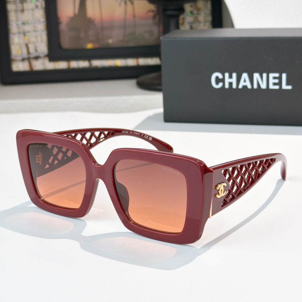 Square sunglasses with red frame and amber-tinted lenses, gold logo on side