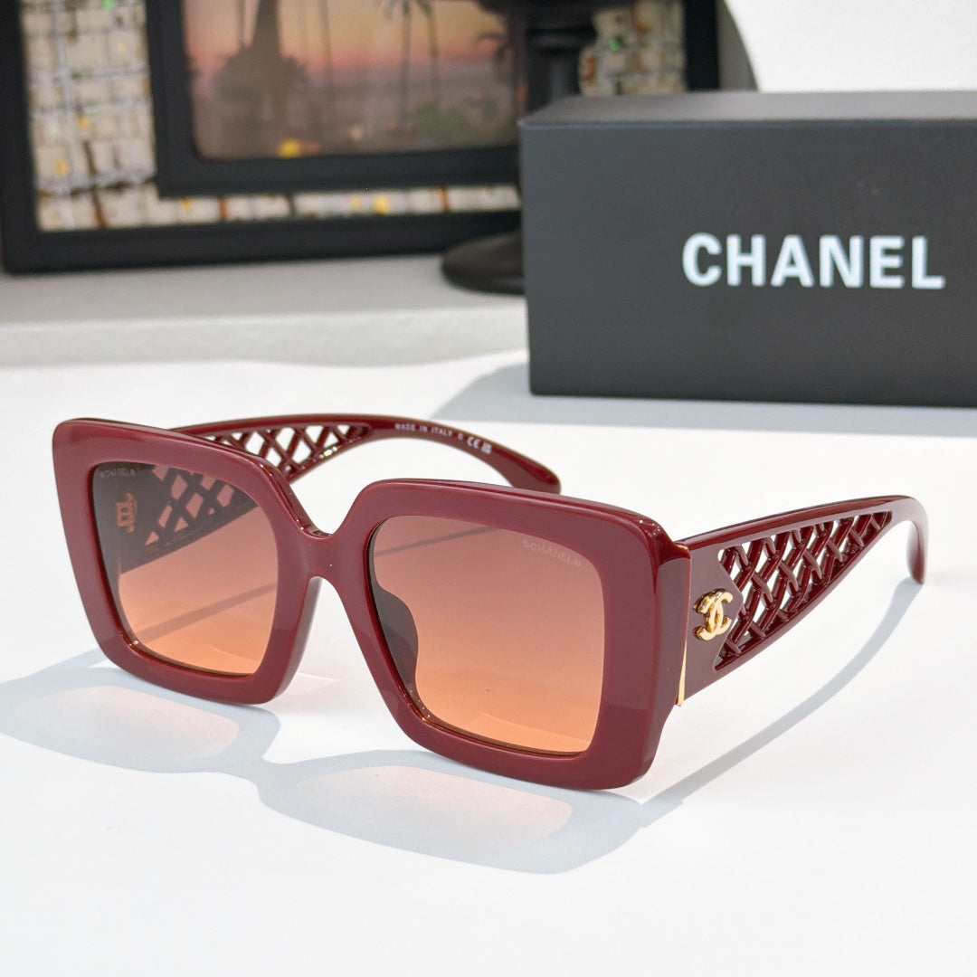 Square sunglasses with red frame and amber-tinted lenses, gold logo on side