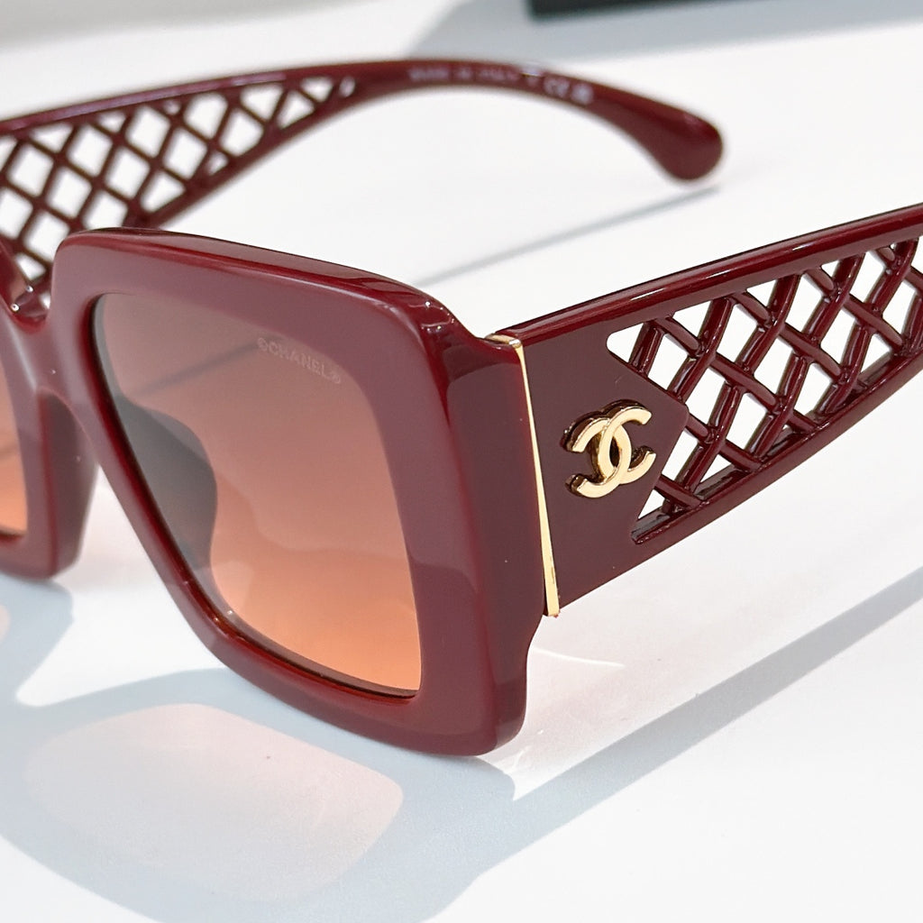 Red square sunglasses close-up with lattice temple and gold CC logo, tinted lenses