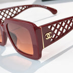 Red square sunglasses close-up with lattice temple and gold CC logo, tinted lenses