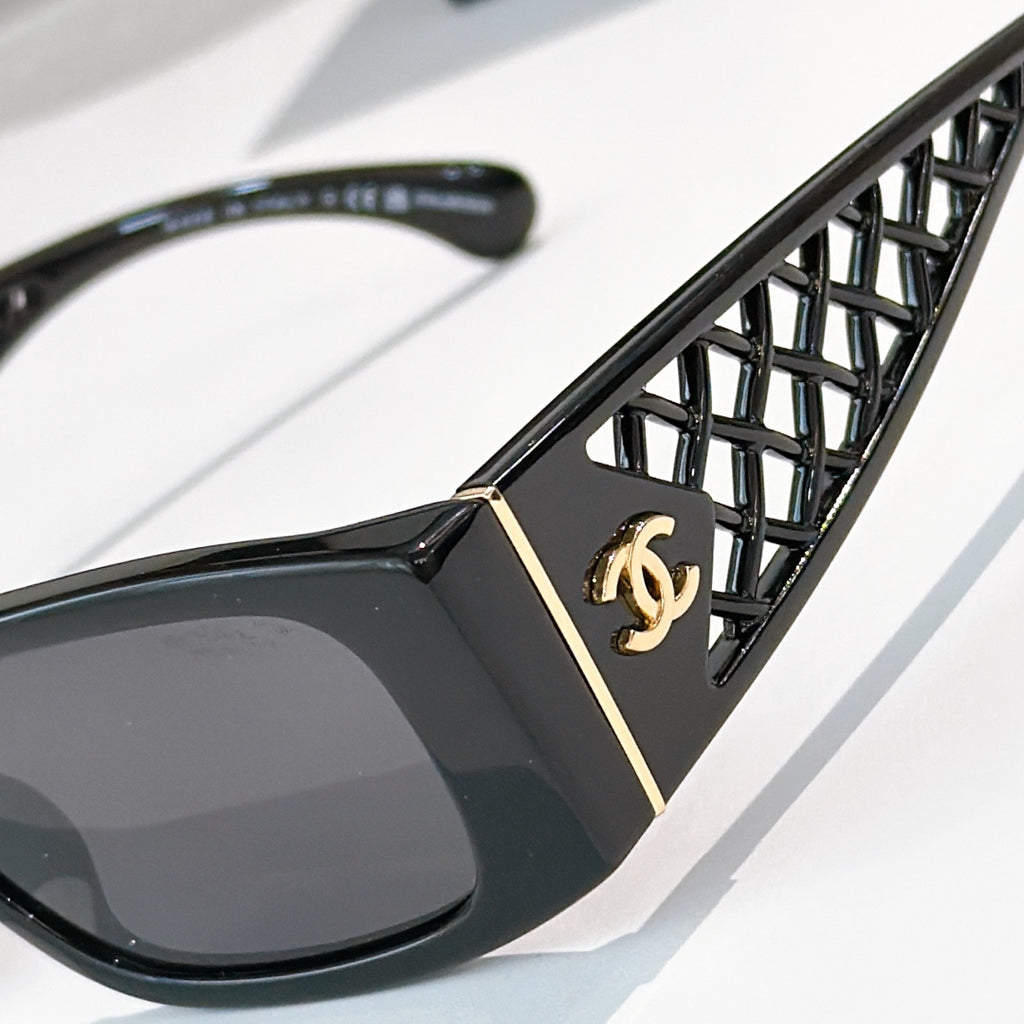 Black sunglasses close-up: diamond-pattern temple with gold Chanel emblem