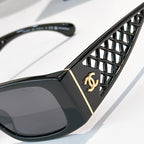 Black sunglasses close-up: diamond-pattern temple with gold Chanel emblem