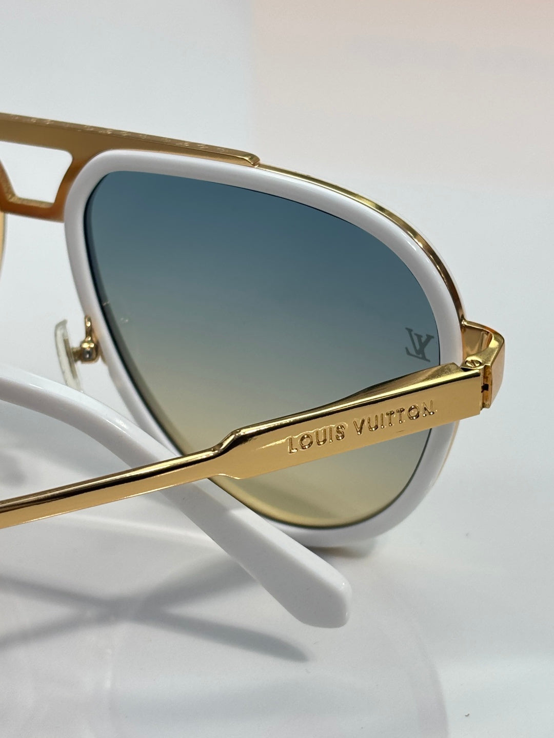 Louis Vuitton sunglasses close-up, white frame with gold-tone bridge and lens logo